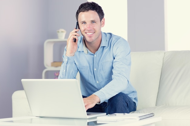 Laughing casual homem usando laptop e telefonando