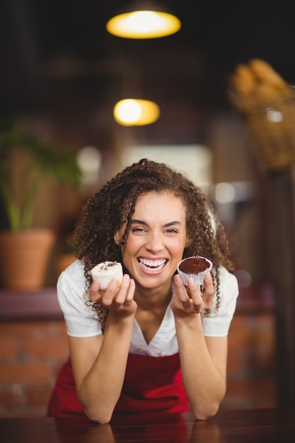 Foto laughing garçonete mostrando dois cupcakes