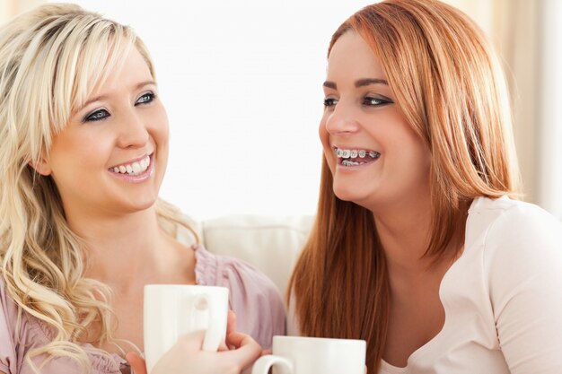 Laughing Young Women sentado em um sofá com copos