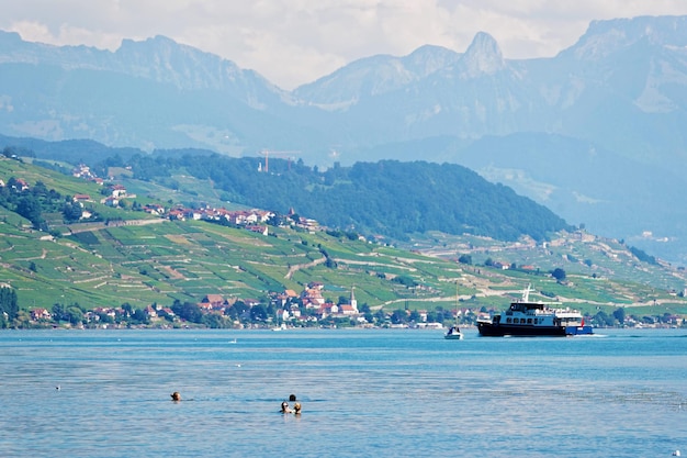 Lausanne, Suíça - 26 de agosto de 2016: Pessoas nadando e balsa de água no Lago Genebra no aterro Ouchy em Lausanne, Suíça. Pessoas a bordo