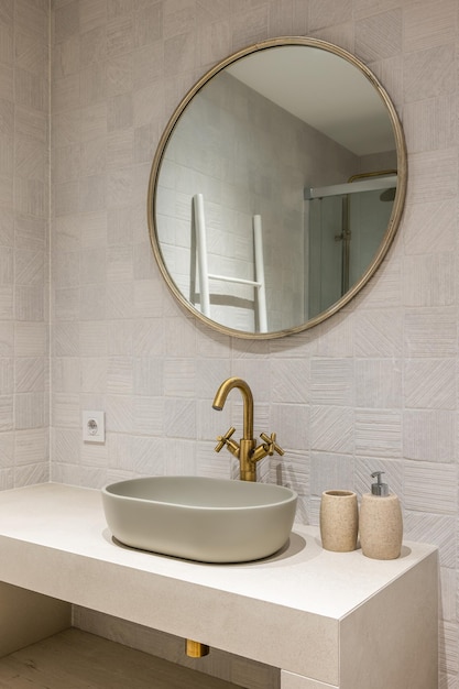 Lavabo de forma ovalada elegante y elegante sobre una encimera de mármol blanco con un elegante grifo de color cobre arriba