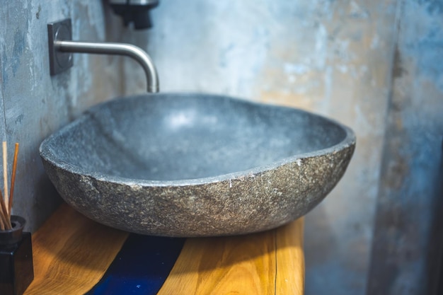 Lavabo de piedra negra de lujo con grifo sobre encimera de madera en un baño moderno y minimalista interior escandinavo