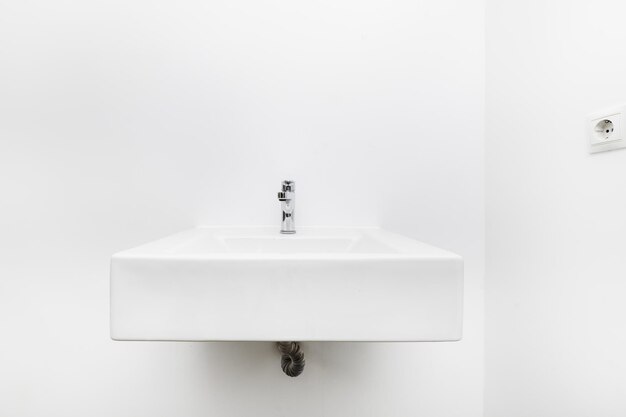 Foto lavabo de porcelana blanca colgado en la pared de un baño sencillo