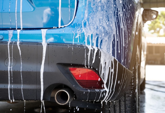 Foto lavado de automóviles azul con espuma de jabón blanco y servicio profesional de cuidado de automóviles concepto de servicio de limpieza de automóviles