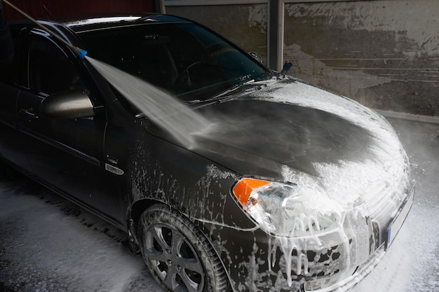 Lavado de autos Limpieza de un auto con agua a alta presión en un lavadero de autos