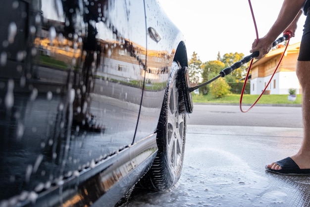 Lavado de un coche negro con espuma activa Limpieza de ruedas