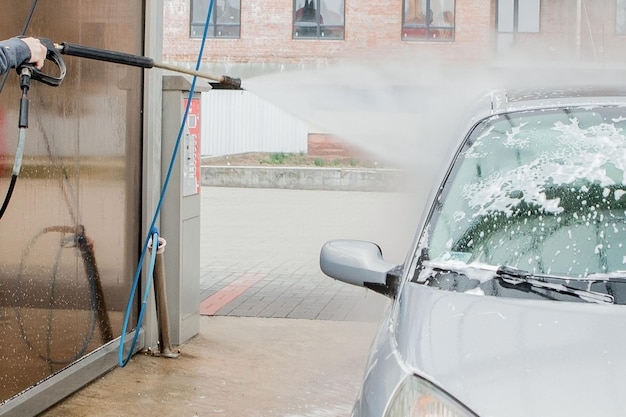 Foto lavado de coches con espuma en la estación de lavado de coches lavado de automóviles máquina de lavado en la estación concepto de lavadeo de automóviles coche en espuma