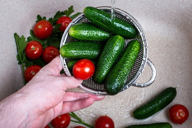 Lavado de manos del hombre tomates y pepinos frescos