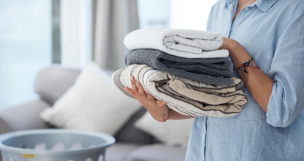 Lavado de manos y limpieza de primavera con una mujer que sostiene un montón de toallas limpias en la sala de estar de su casa Hospitalidad de telas y lavado con una limpiadora en su apartamento para las tareas del hogar
