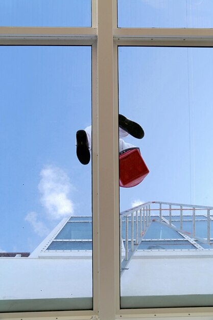 Lavador de janelas visto através da janela contra o céu