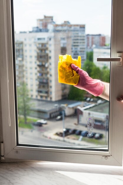 La lavadora limpia la ventana con un trapo en la casa de apartamentos