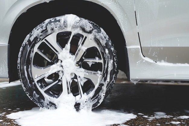 Lavagem de carro com sabonete de espuma ativa. limpeza do pneu da roda. conceito de serviço de limpeza comercial.