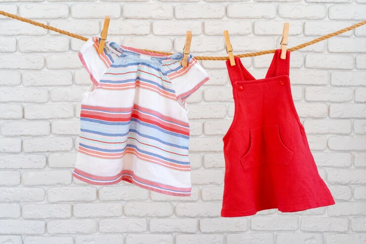Foto lavagem de roupas de bebê presas em uma corda para secar