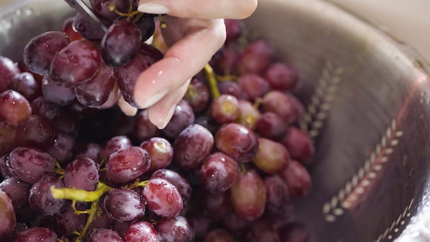 Lavagem de uvas vermelhas sem sementes em coador de aço inoxidável.