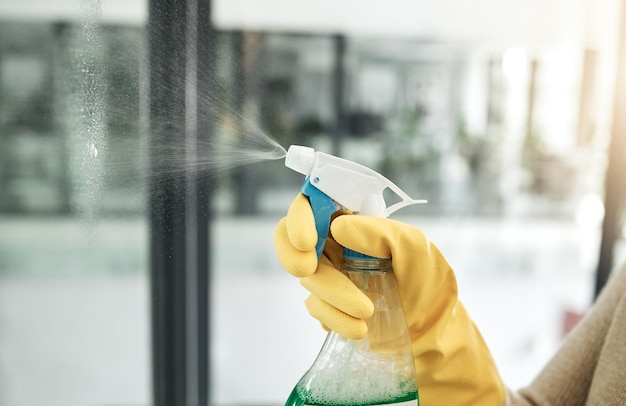 Foto lavagem limpa e tarefas diárias em casa com um frasco de spray de higiene doméstica para janelas dentro closeup de trabalho de limpeza lavando e trabalhando a mão com luvas pulverizando limpador de vidro com cuidado dentro de casa