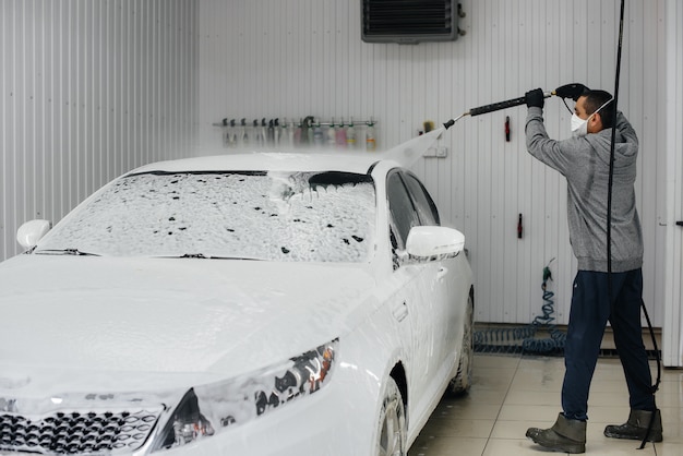 Lavagem moderna com espuma e água de alta pressão de um carro branco.