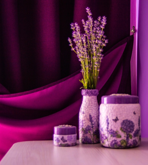 Lavanda en el jarrón sobre la mesa. Cortina púrpura y fondo violeta de la pared.