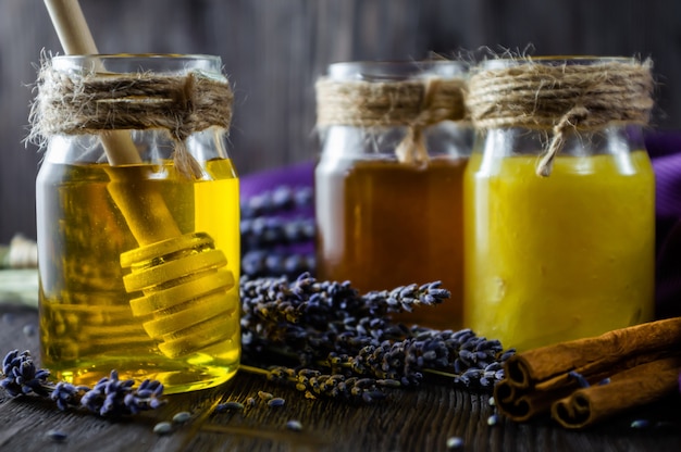 Lavanda y miel herbaria en los tarros de cristal en la tabla de madera oscura.