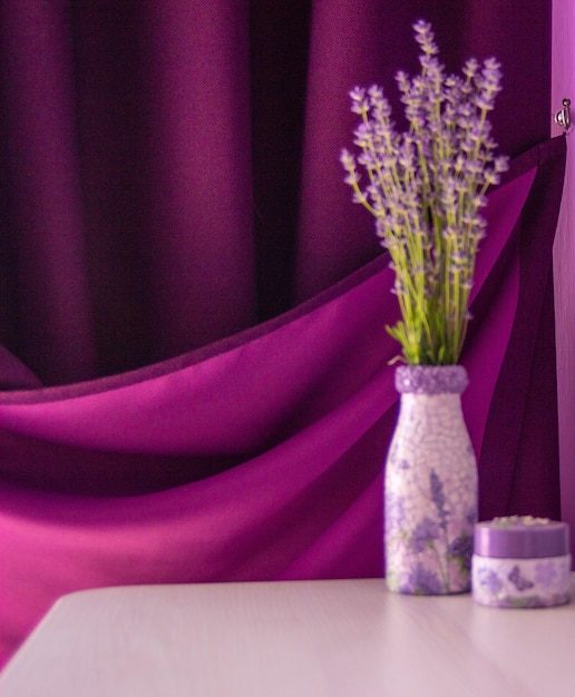 Lavanda no vaso sobre a mesa. cortina roxa e fundo de parede violeta.