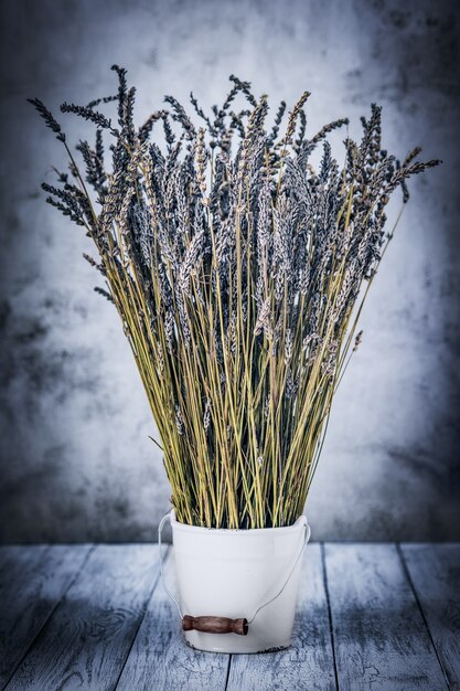 Lavanda seca en un balde blanco sobre un fondo de madera