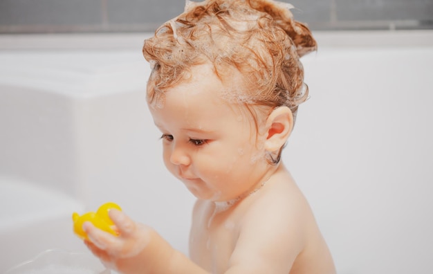 Lavando bebê adorável no banheiro Criança com espuma de sabão no cabelo tomando banho Retrato aproximado de cuidados de saúde de criança sorridente e higiene infantil Banho de espuma infantil