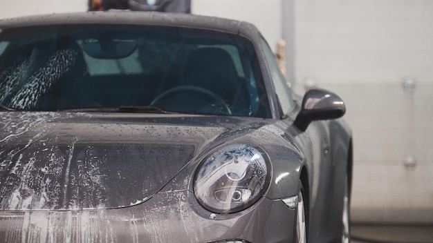 Lavando carro esporte na espuma por mangueiras de água