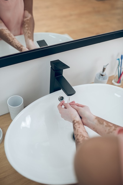 Lavando. feche a foto de mãos femininas sob a bacia de água