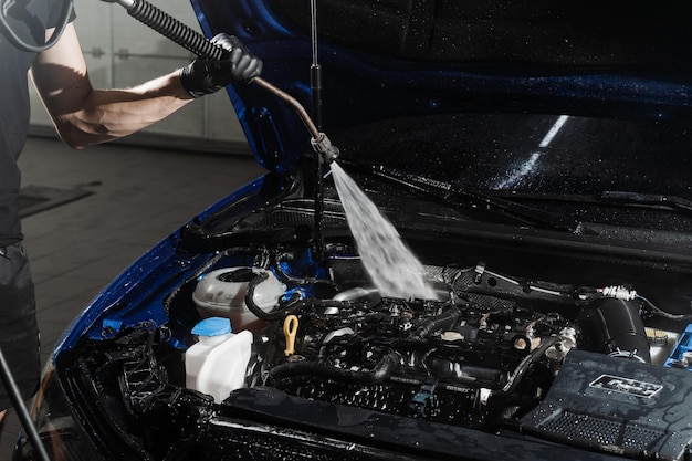 Lavando o motor do carro com água no detalhamento do serviço automático Detalhando o motor de limpeza da poeira e sujeira Despejando água no motor do carro