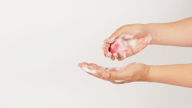 Lavar as mãos com espuma e sabão rosa em fundo branco Foto de estúdio