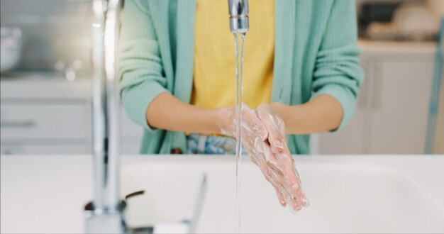 Lavar as mãos da mulher e a água do lavatório da cozinha com sabão para limpeza e bem-estar Segurança doméstica e proteção contra vírus de uma pessoa com cuidados de saúde sanitários em uma casa para cuidados com a pele e higiene