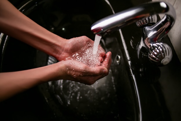 Lavar as mãos de um adolescente na pia debaixo da torneira com água limpa