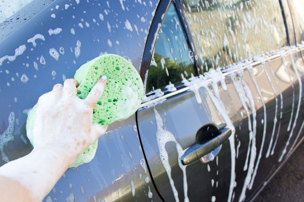 Lavar un automóvil con una toallita con las manos, primer plano