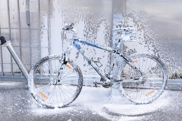 Lavar una bicicleta con un chorro de espuma en un lavadero de autos La bicicleta está cubierta con espuma Autoservicio de mantenimiento de bicicletas