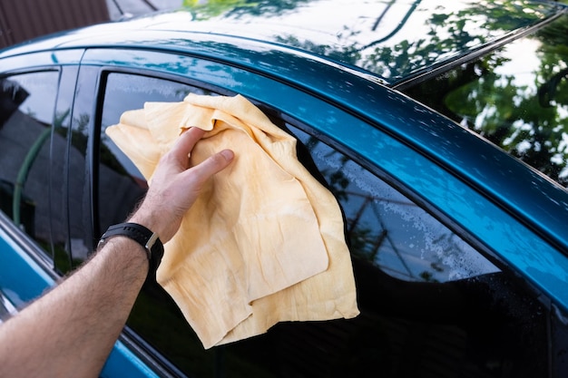 Foto lavar o carro ao ar livre durante o dia. limpe os restos de gotas com uma microfibra