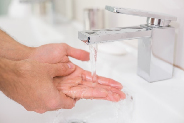 Lavarse las manos con agua corriente en el lavabo del baño