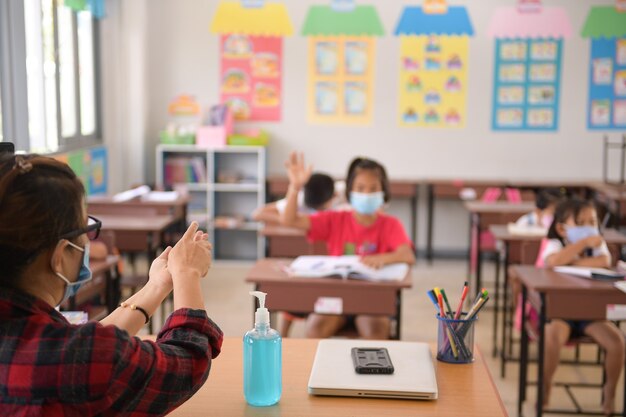 Foto lavarse las manos con gel desinfectante para la prevención de la enfermedad por coronavirus (covid-19) en el aula lavarse las manos con desinfectantes con alcohol o gel con alcohol de una botella con bomba en un área pública.