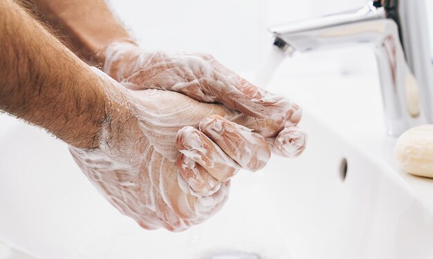 Lavarse las manos con jabón con agua corriente en el fregadero, higiene de manos para la prevención del Coronavirus 2019-ncov. Protección contra la pandemia del virus Corona limpiando las manos con frecuencia.