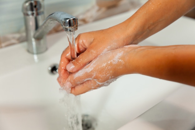 Lavarse las manos con jabón con agua corriente del grifo. manos femeninas bajo el chorro de agua.