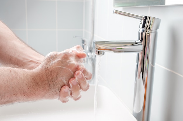 Lavarse las manos con jabón en el baño.