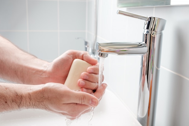 Foto lavarse las manos con jabón en el baño.