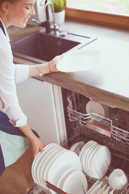 Lavavajillas mujer joven en la cocina haciendo limpieza de tareas domésticas