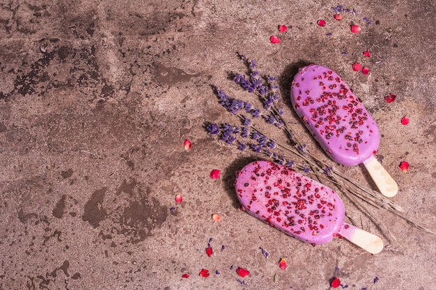 Lavendel Eis. Blumenstrauß, rosa Rosenblätter. Trendiges hartes Licht, dunkler Schatten. Marmorsteinhintergrund, Draufsicht, flacher Lay