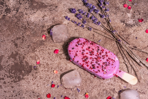 Lavendel Eis. Blumenstrauß, rosa Rosenblätter. Trendiges hartes Licht, dunkler Schatten. Marmorsteinhintergrund, Draufsicht, flacher Lay