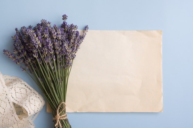 Lavendelblumen in einem Blumenstrauß auf dem Tisch nahe einem leeren Blatt alten Papiers für Text.