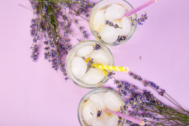 Lavendellimonade mit Zitrone und Eis auf purpurrotem Hintergrund.