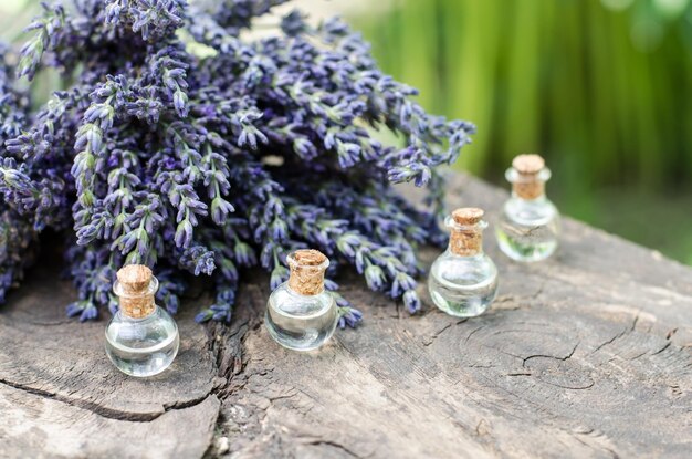 Lavendelöl in kleinen Flaschen auf einem Holztisch Lavendelöl und Lavendelbouquet