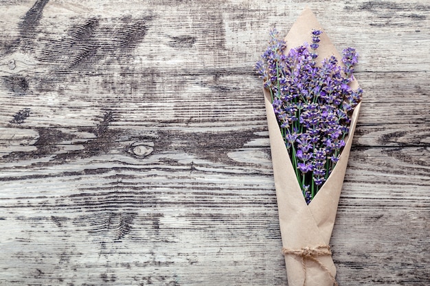 Lavendelstrauß in Papierverpackung mit Kopienraum für Text. Frischer Lavendelblumengrußblumenstrauß auf altem rustikalem Holztisch. Flatlay-Blumenblüte im französischen Provence-Stil. Lavendel Aromatherapie