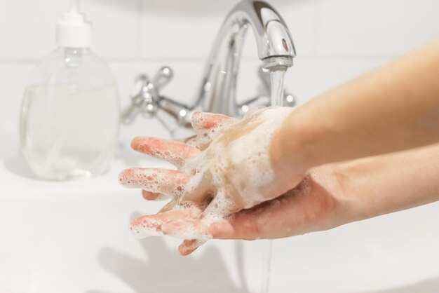 Lávese las manos Frotándose los dedos Lavarse las manos con jabón antibacteriano con la técnica adecuada sobre el fondo del agua que fluye en el baño blanco Prevención coronavirus Limpieza y desinfección
