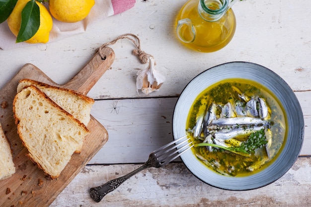 Foto lay flat de anchoas marinadas en jugo de limón con aceite de oliva ajo y perejil. comida tradicional mediterránea de verano