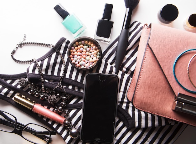 Lay flat de bolso de mujer de cuero rosa con accesorios cosméticos y teléfono inteligente